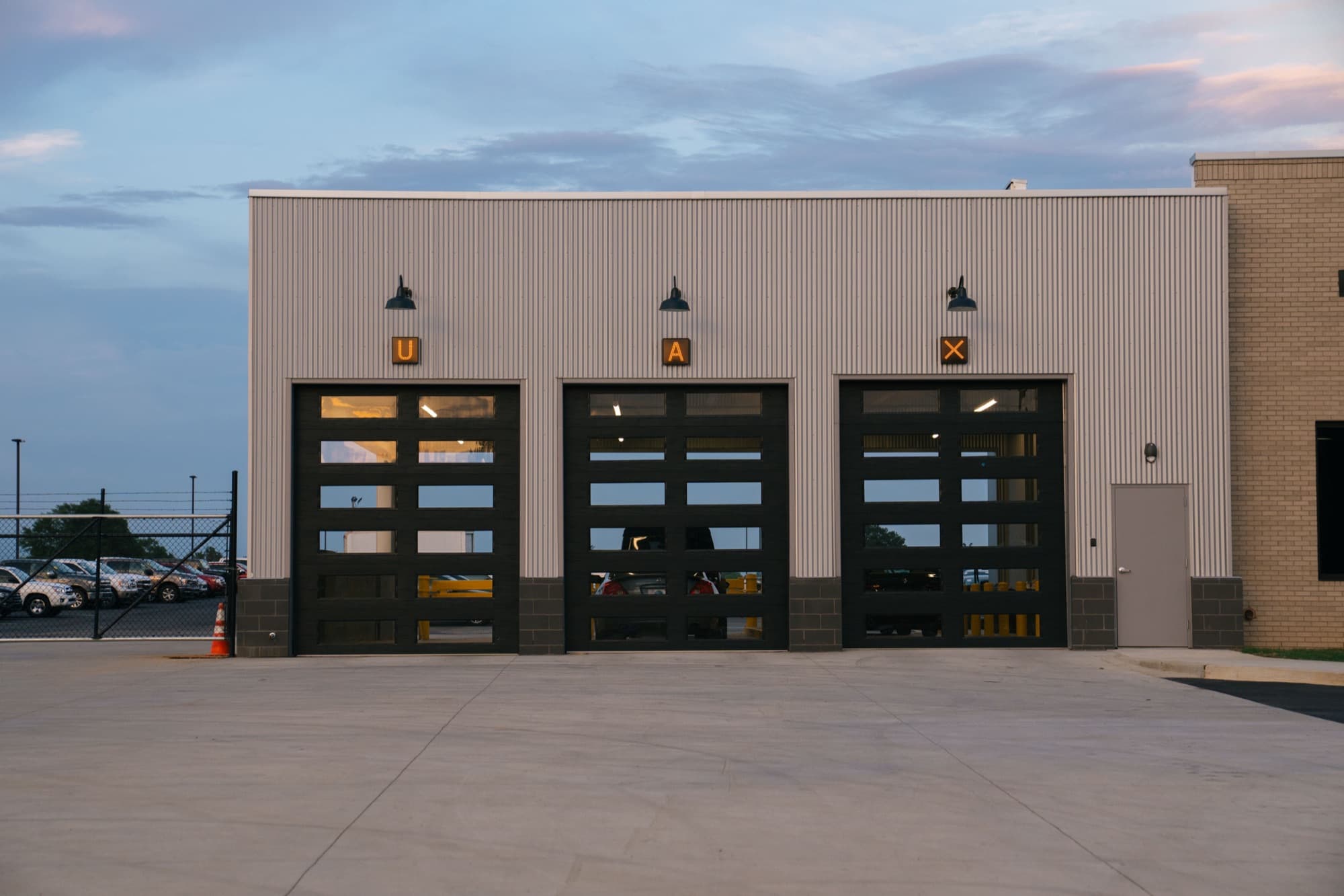 UAX letters mounted on three garage bay doors at dusk.