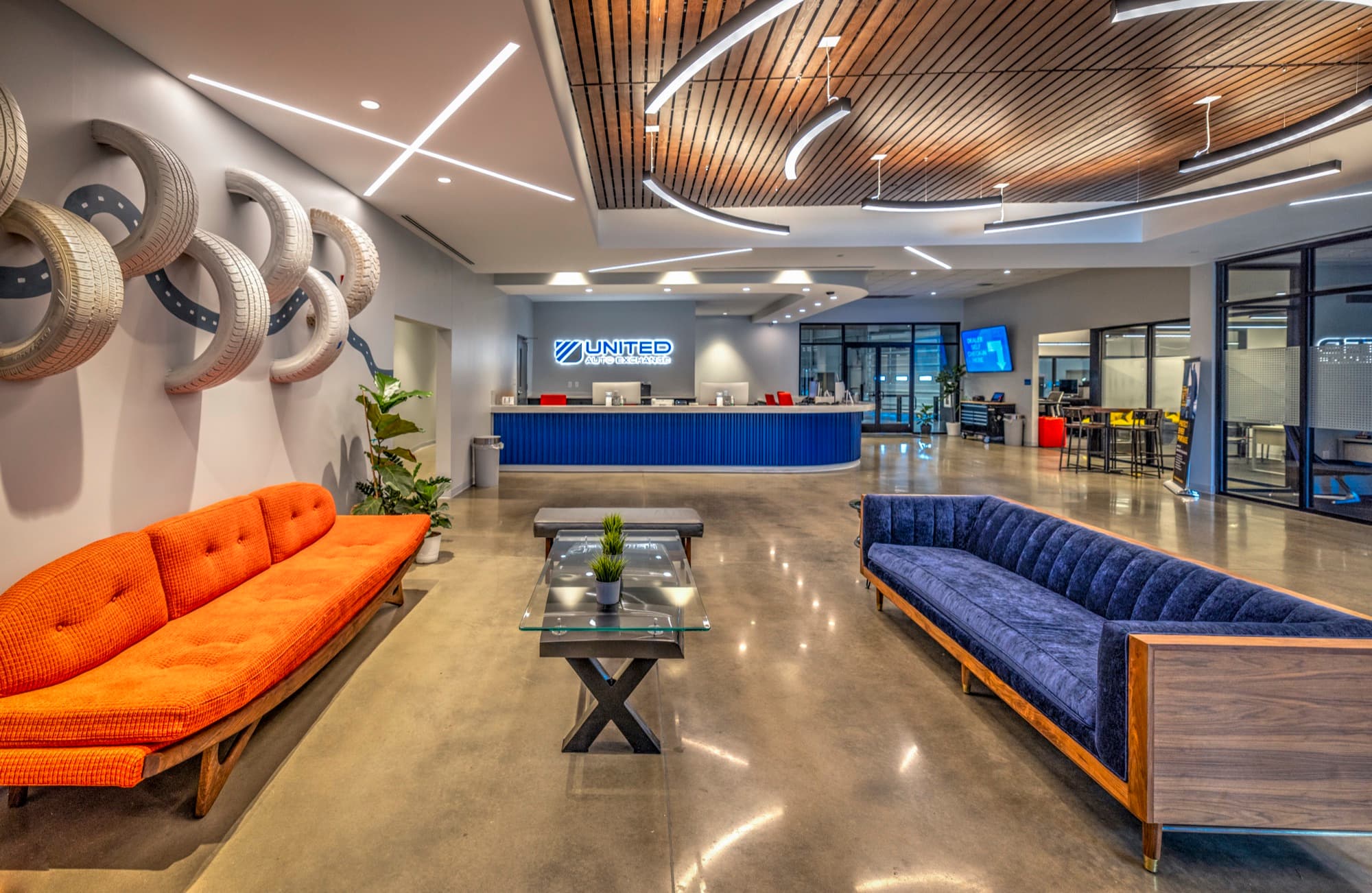 UAX lobby interior — orange sofa, tire-sculpture wall, blue United Auto Exchange counter.